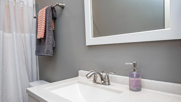 Une salle de bain avec un lavabo blanc, un miroir et un rideau de douche.