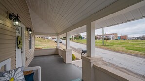 A covered porch with a concrete floor, a white bench, and a door with a window. - Cheerful Pet-Friendly Bungalow 1 Block from Downtown Laurens (Laurens)