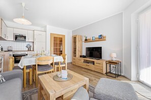Un apartamento moderno con comedor, cocina, sala de estar y televisor.