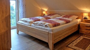 Huoneessa on puinen sänky, josta on näkymä ikkunasta, yöpöytä ja matto.