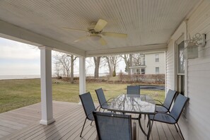 A covered patio with a glass table and chairs, overlooking a grassy area and a house. - Spacious Lakefront House w/ Backyard Fire Pit (Monroe)
