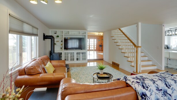 Ein geräumiges Wohnzimmer mit einer Ledersofa, einem Flachbildfernseher und einer Treppe, die zu einer oberen Etage führt.
