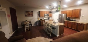 Una cocina compacta con armarios de madera, una isla central con taburetes de bar, un microondas y un refrigerador.