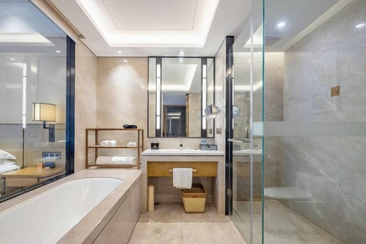 Un baño moderno con una bañera grande, una ducha con cerramiento de vidrio y un tocador con espejo.