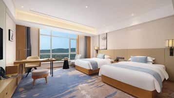 Une chambre d’hôtel avec deux lits, un bureau, une chaise, une petite table et une grande fenêtre.