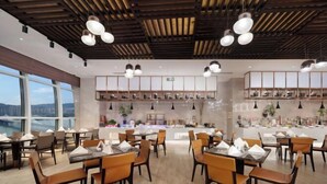 Een modern restaurant met houten balken in het plafond, hangende lampen en uitzicht op een brug. Tafels zijn gedekt met witte servetten en borden.