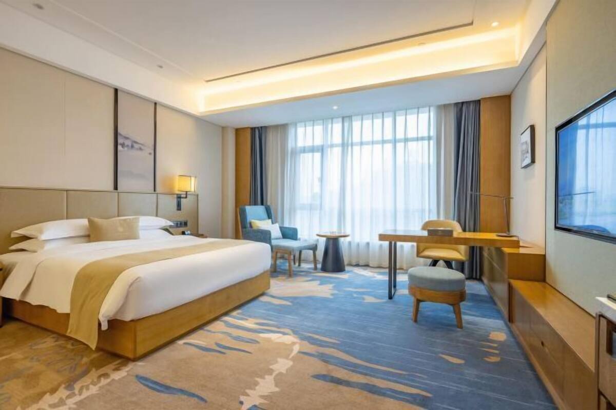 Una habitación de hotel con una cama grande, un escritorio, una silla y un televisor.