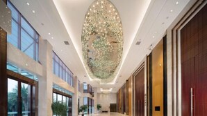 Een ruime hotel lobby met een hoge plafond, grote ramen en een centrale kroonluchter.
