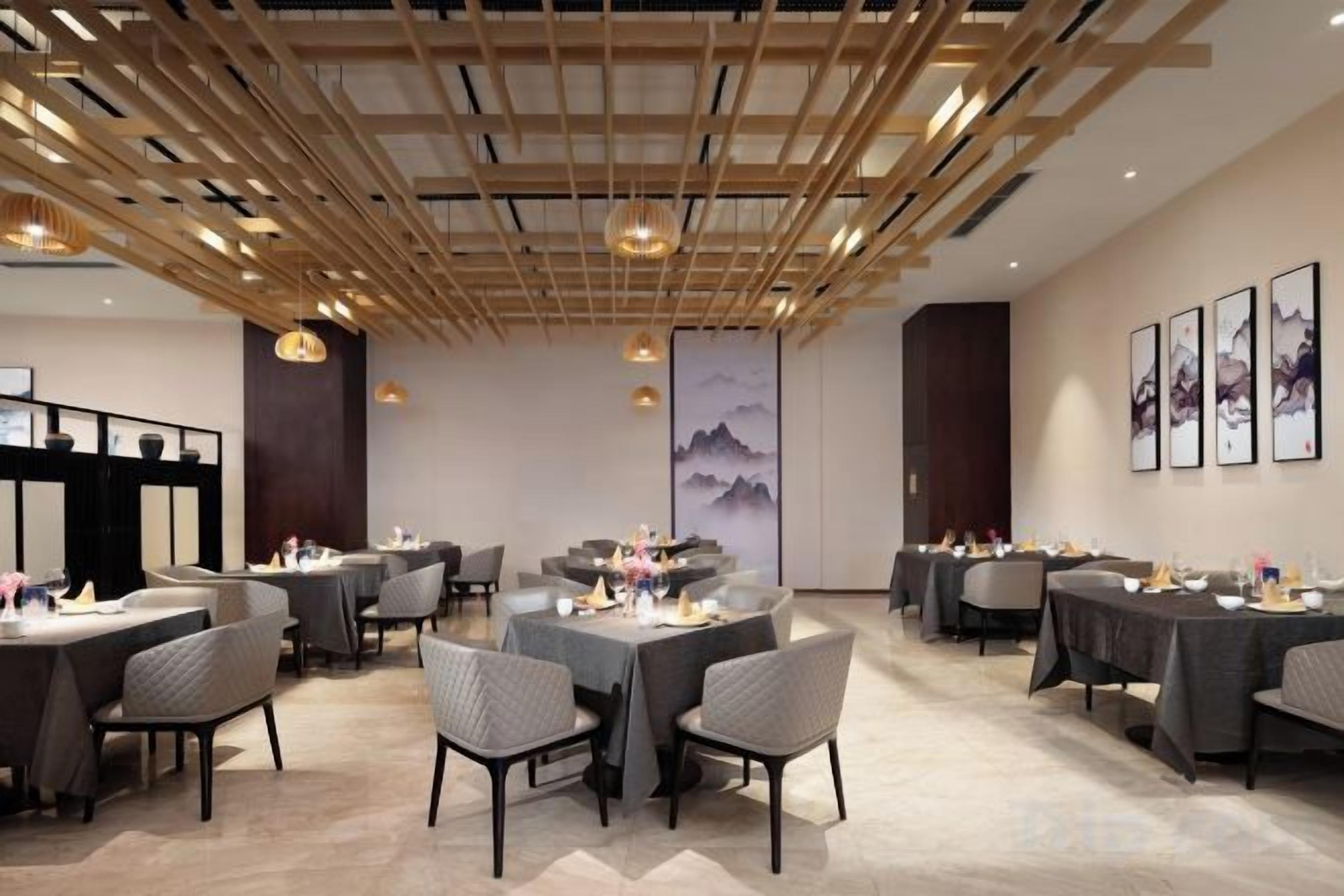 Un espace repas avec des tables et des chaises, des poutres en bois au plafond et des œuvres d’art accrochées aux murs.