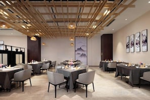 A dining area with tables and chairs, wooden ceiling beams, and artwork on the walls. - Haoweiyi International Hotel (Nanbu County)
