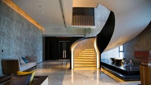 Un intérieur moderne avec un escalier à volutes, un espace salon et un comptoir d’accueil.