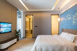 Ein modernes Hotelzimmer mit einem großen Bett, einem wandmontierten Flachbildfernseher und einer Zimmerpflanze.