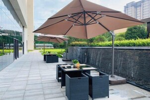 Un patio al aire libre con mesas, sillas, sombrillas y un muro de piedra.