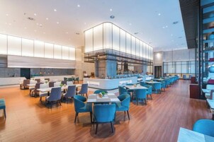 Un restaurante moderno con una barra central, varias mesas y suelo de madera.