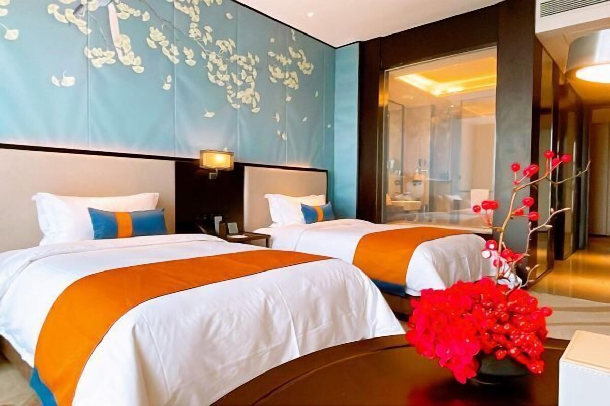 Ein Hotelzimmer mit zwei Betten, einem großen Fenster und einer dekorativen Wand.