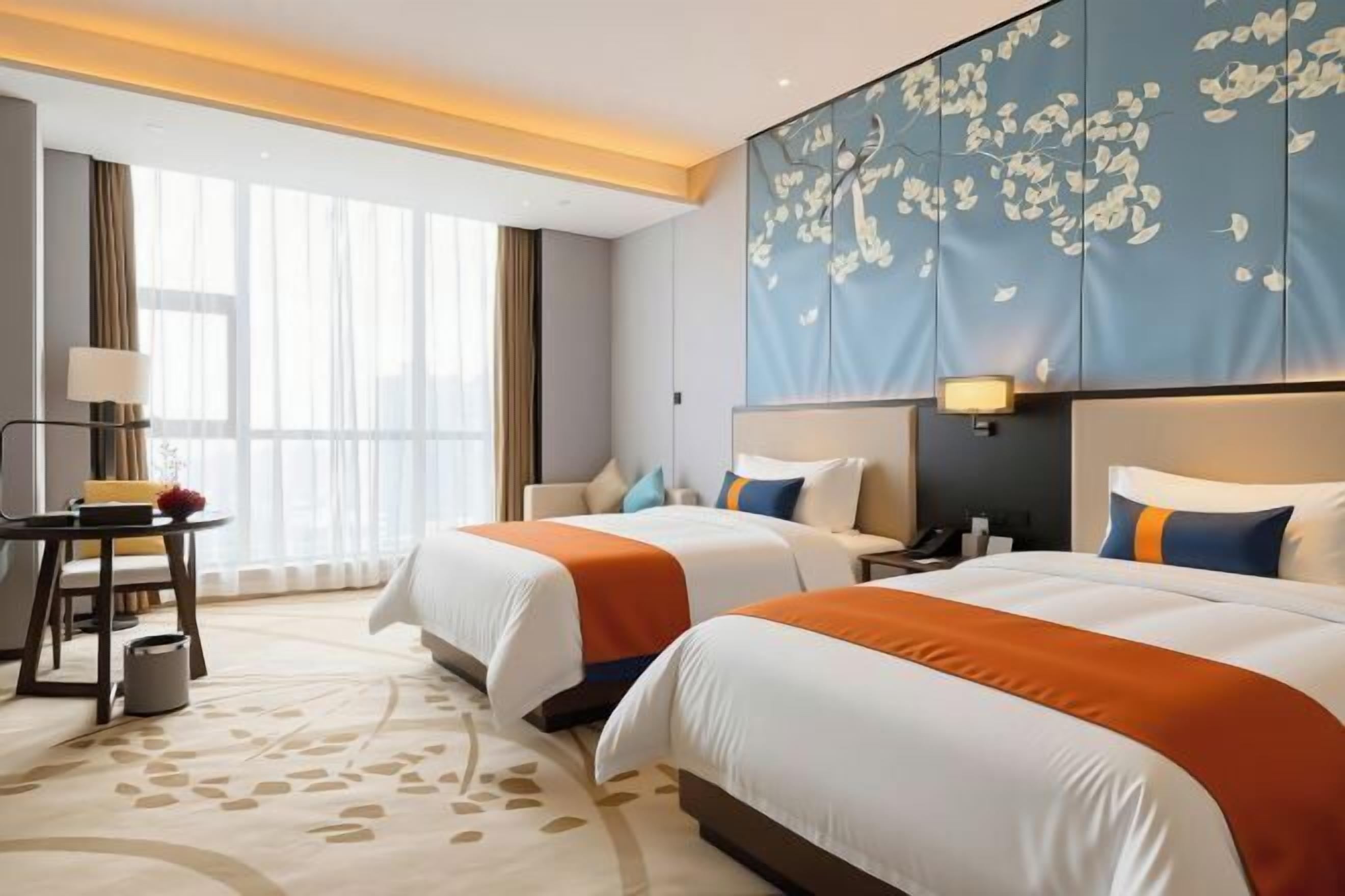 Habitación de hotel con dos camas, un escritorio, una lámpara y un cabecero grande con estampado floral.
