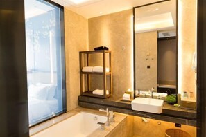 Ein modernes Badezimmer mit einem großen Spiegel, einer Badewanne und einem Handtuchregal.