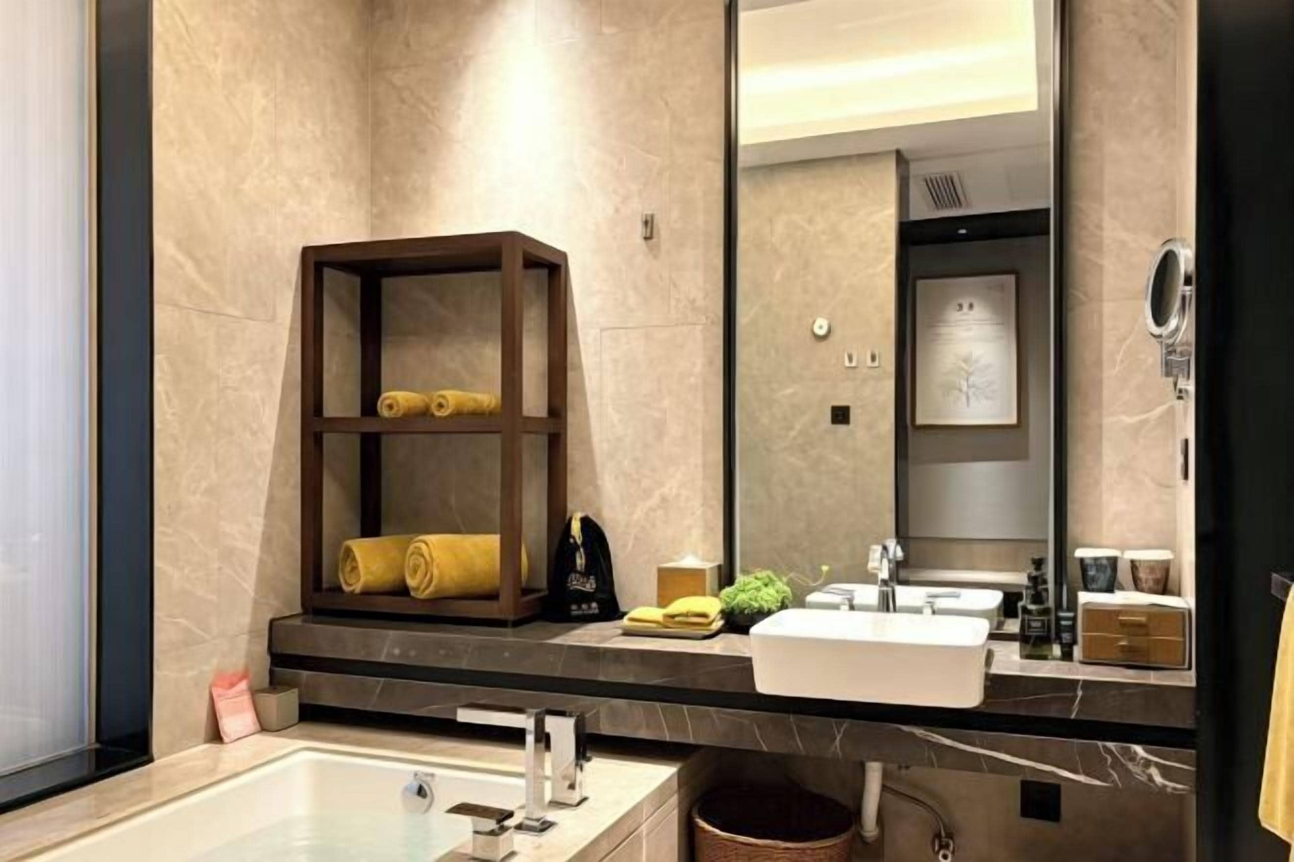 Une salle de bain moderne avec un grand miroir, une baignoire, un lavabo et une étagère avec des serviettes.
