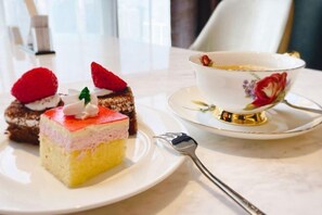 Ein Dessertteller mit Kuchenstück und einer Teetasse auf einem Tisch.