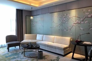 Un salon moderne comprenant un canapé, un fauteuil, une table basse et un mur décoratif orné de motifs floraux.