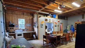 A compact kitchen with wooden cabinets, a dining table, and chairs. - Bunkhouse Dry Cabin Farm Rustic private secure (Lebanon)