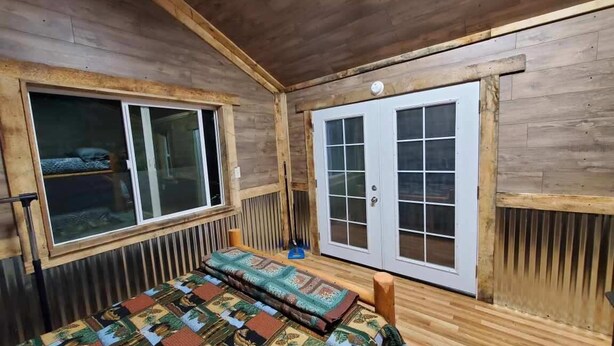 A wooden cabin room with a bed, a window, and a sliding door. - Bunkhouse Dry Cabin Farm Rustic private secure (Lebanon)