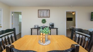 Comedor con mesa y sillas de madera, una estación de café y una obra de arte enmarcada en la pared.