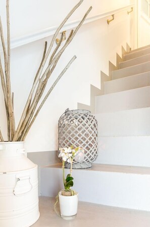 A staircase with a white wall, a white pot with a plant, and a white lantern. - Appartement Tessa, Deutschland (Sylt-Ost)