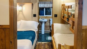Habitación pequeña con dos camas, un lavamanos y una ventana con cortinas.
