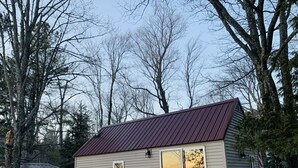 Una casita de una sola planta con techo de metal, puerta corredera de vidrio y una ventana pequeña.