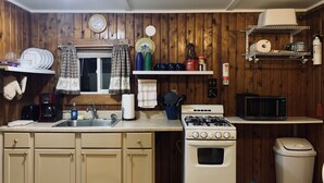 Cocina con paredes de madera, estufa, microondas y lavabo.