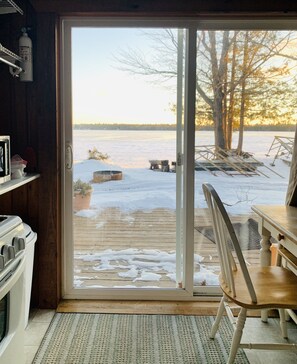 Een kamer met een schuifdeur die uitkomt op een terras met houten vloer, een stoel en een tafel.