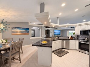A modern kitchen with a central island, built-in appliances, and a dining area with a view.