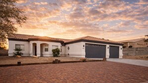 A two-story house with a tiled roof, a garage, and a paved driveway.