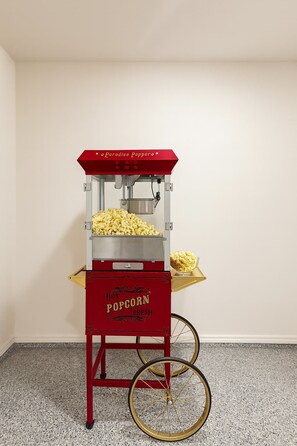 A vintage-style popcorn machine with a red and gold design, labeled "Paradise Pappero," and a bowl of popcorn on its side.