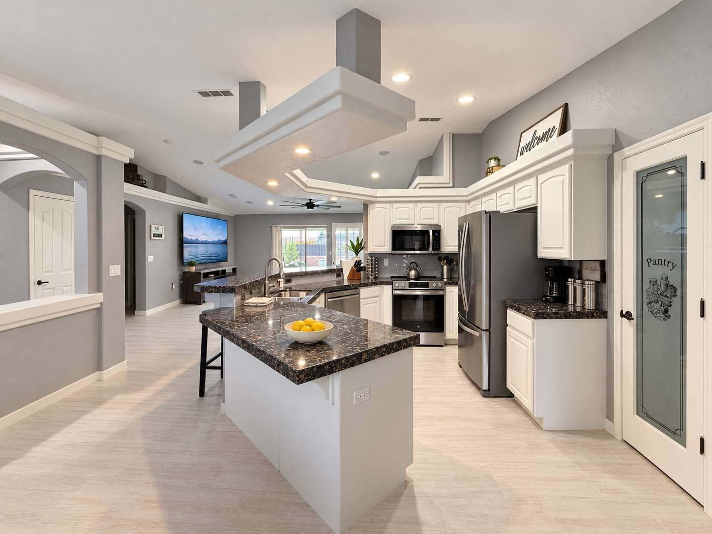 A modern kitchen with a central island, stainless steel appliances, and a view of the outdoors.