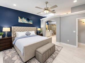 A bedroom with a bed, nightstands, a ceiling fan, and a bathroom visible through an archway.