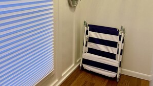 A bathroom with a striped towel rack, a shower curtain, and a window with blinds. - Beautiful Beachside Bungalow (Kailua)