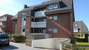 Un immeuble résidentiel à plusieurs étages, doté d’une façade en briques, de balcons et d’une entrée de garage.