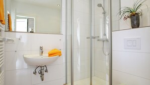 Une salle de bain moderne avec une douche à parois de verre, un lavabo blanc et des toilettes.