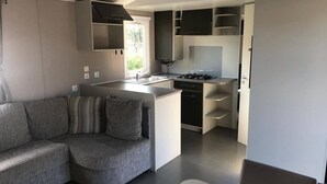 A compact living space with a kitchenette, a sofa, and a dining area. - Mobile Home (Lattes)