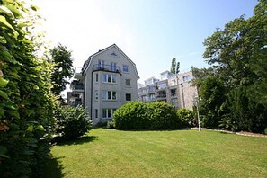 Een meerlaags woongebouw met een verzorgd gazon en volwassen bomen.
