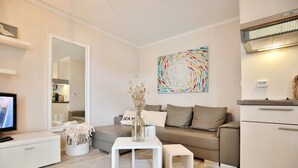 Un salón moderno con un sofá, una mesa de centro, un televisor y un cuadro en la pared.