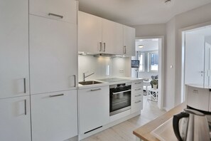 Una cucina moderna con mobili bianchi, elettrodomestici in acciaio inossidabile e un piano di lavoro in legno.