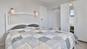 A bedroom with a bed, a wardrobe, and a bedside table.