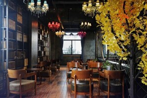 A cozy restaurant with wooden tables and chairs, hanging lights, and a large window with a view. - Hefei Gui Jing Wan Hotel (Hefei)