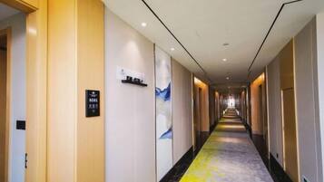 A hotel hallway with a long corridor, doors on the left, and a sign indicating room number SG01.
