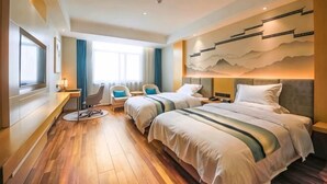 A hotel room with two beds, a desk, a chair, and a large window.