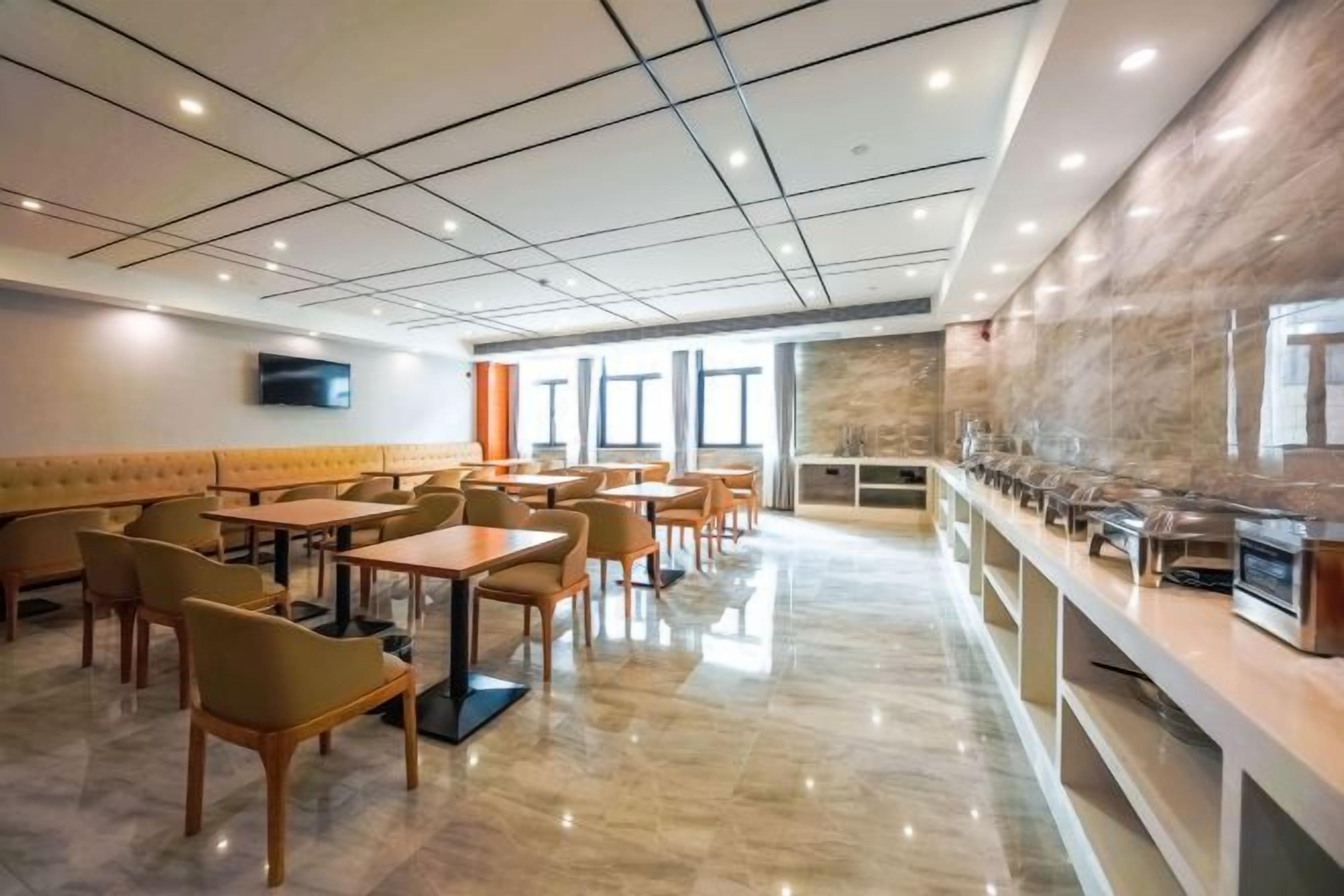 A modern dining area with a long counter, multiple tables, and a seating area with cushioned benches.
