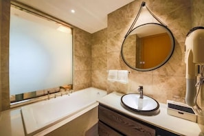 A modern bathroom with a bathtub, a round mirror, a sink, and a towel rack. - Hefei Gui Jing Wan Hotel (Hefei)
